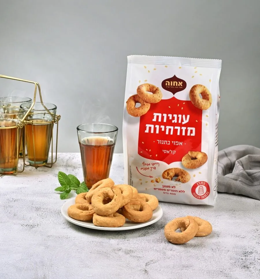 שקית עוגיות מזרחיות של אחוה על שיש ליד כוס תה וצלחת עוגיות