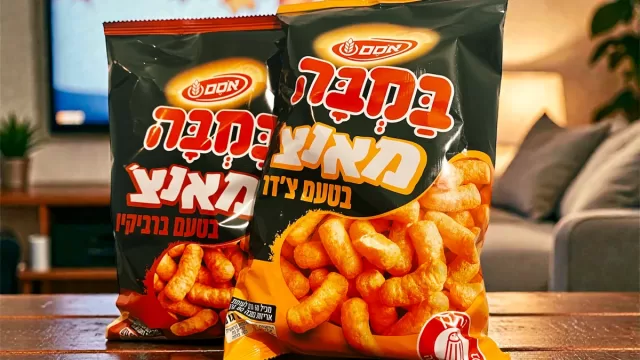 שקיות של חטיף במבה מאנצ' בטעמי צ'דר וברביקיו על שולחן בסלון